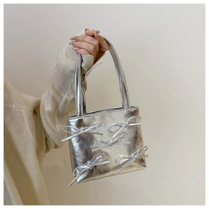 Detail of silver metallic handbag with layered bows and sleek faux leather finish