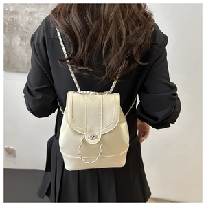 Detailed view of cream-colored PU leather backpack with silver chain straps and metal lock