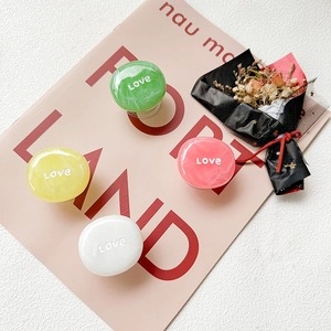 Macro detail of four marble-textured resin phone grips with Love engraving in pastel colors