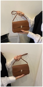 Detailed close-up of brown rectangular shoulder bag with metal lock and smooth texture
