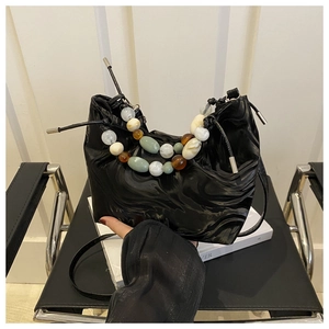 Close-up of black pleated glossy bucket bag with multi-color bead handle and strap
