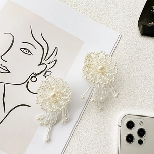 Detail of white pearl flower phone socket with elegant beaded tassels on minimalist desk