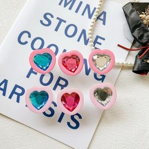 Macro detail of heart-shaped crystal phone grips in candy colors on editorial background