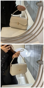 Detail of cream leather shoulder bag featuring an elegant gold twist lock and flap design