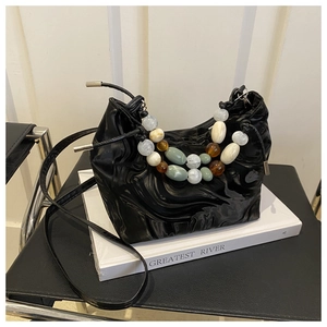 Detail of black glossy pleated bucket bag with decorative colorful oversized beads