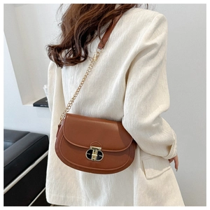 Caramel brown leather saddle bag detail with gold geometric clasp and chain strap