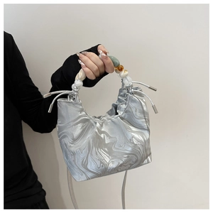 Macro detail of silver drawstring bucket bag with marble texture and colorful beaded handle