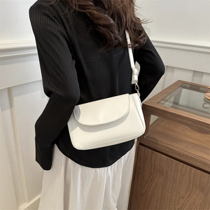 Chic white crossbody bag with rectangular flap and gold buckle on a stylish model