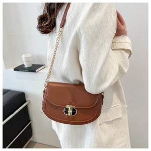 Detailed view of a caramel saddle bag with gold metal buckle and crossbody chain strap