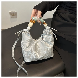 Detailed view of silver marble pattern bucket bag with colorful beaded handle and drawstring