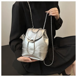 Detail of silver metallic textured bucket bag with chain strap worn on black outfit
