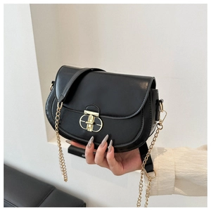 Close-up of black saddle bag featuring gold oval twist lock and metal chain strap