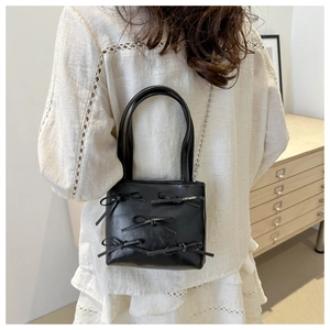 Mini black bucket bag with bows and beaded chain strap on model with white lace