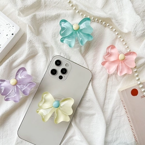 Macro view of pastel bow-shaped collapsible phone grips in mixed colors on fabric