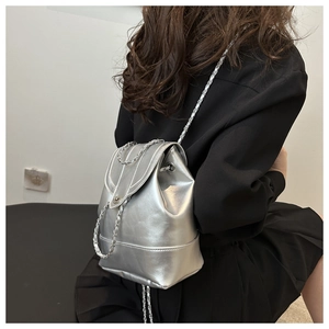Silver metallic leather backpack featuring chain straps shown from a side-back view
