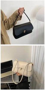 Detail of the minimalist shoulder bag showing the golden metal lock and leather texture