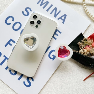 Detail of heart-shaped crystal phone sockets in clear and rose pink on white smartphones