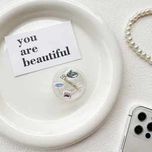 Macro detail of round collapsible phone grip with colorful rhinestones and Diamonds text