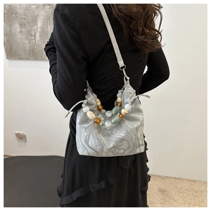 Detail of marble pattern tote bag featuring colorful beaded handle and drawstring closure