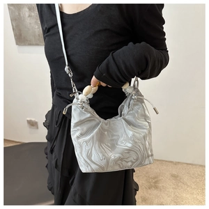 Detail of silver marble textured crossbody bag with decorative bead handle and drawstring