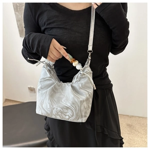 Detail of silver marble print bucket bag with large decorative bead handle and satin finish