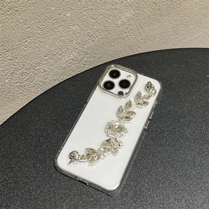 Detail of luxury iPhone case featuring a rhinestone leaf chain on a transparent cover