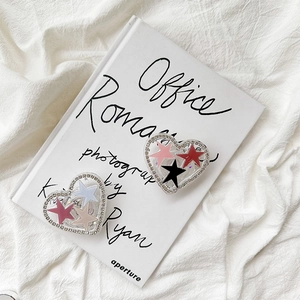 Detail of heart-shaped phone grips with star accents and rhinestones on white fabric