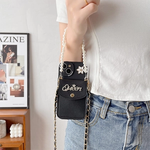 Detail of black iPhone wallet case with Queen metal emblem and pearl strap