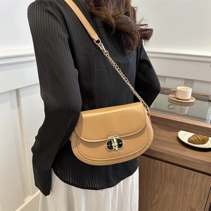 Minimalist camel leather saddle bag with gold metal twist lock and chain strap
