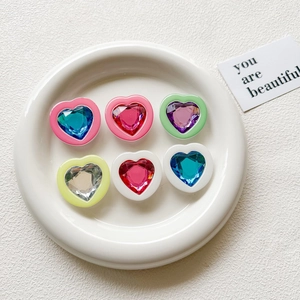 Detailed view of colorful 3D heart-shaped gem phone grips on a white ceramic plate