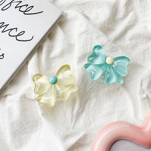 Detail of floral bow phone grip with translucent resin material on soft fabric background