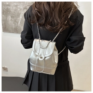 Detail of silver metallic mini backpack with chain strap on model in black suit