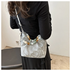Detail of grey marble pattern handbag with colorful beaded handle and drawstring closure