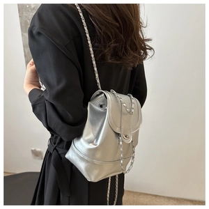 Detailed back view of a silver metallic mini backpack with chain straps on a model