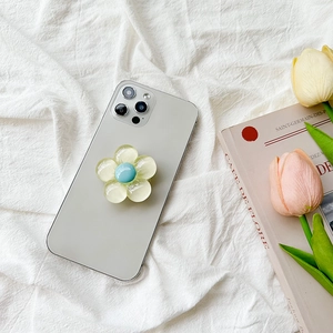 Pastel flower cell phone grip with yellow petals and blue core on a gray smartphone
