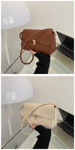 Detail view of brown and beige shoulder bags with golden metal clasps on a glass desk