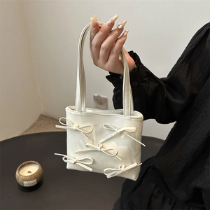 Minimalist white leather handbag with elegant bow details and versatile shoulder strap