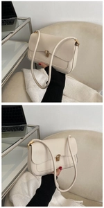 Detail view of cream leather shoulder bag featuring a sleek gold metal buckle closure