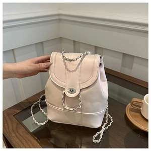 Detail of light pink PU bucket bag featuring silver chain straps and turn-lock closure