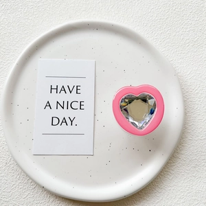 Detailed view of pink heart phone grip with faceted crystal gem on white ceramic plate