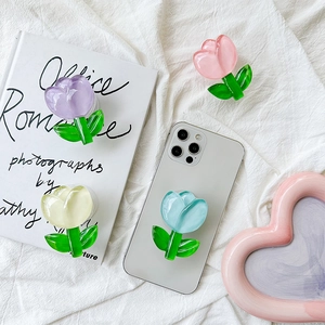 Flat lay of colorful tulip flower phone grips on a soft white fabric background