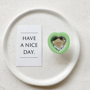 Detail view of heart-shaped phone grip with faceted crystal inlay on a minimalist tray