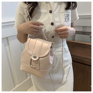 Detailed side view of pearlescent pink mini backpack with silver chain strap on model
