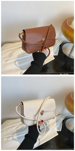 Detailed view of brown and cream leather bags with unique golden metal clasps and thin straps