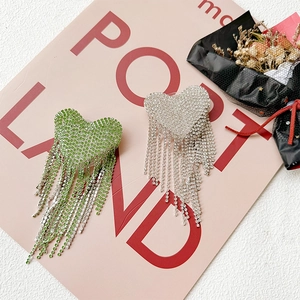Detailaufnahme von Herz-Strass-Quastenohrringen auf dekorativem rosa Hintergrund