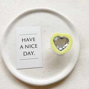 Detail of yellow heart phone grip with large faceted crystal center on ceramic tray