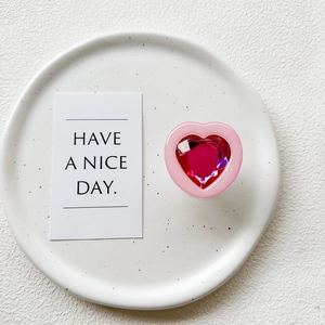 Detail of candy heart phone grip with faceted pink gemstone on white ceramic plate
