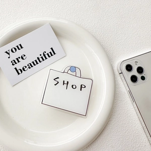 Close-up of minimalist SHOP bag phone grip holder on white decorative tray