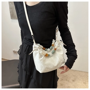Detail of marble pattern shoulder bag with beaded handle and drawstring closure