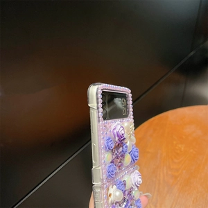 Macro detail of Samsung Z Flip6 case with purple resin roses, pearls and rhinestones